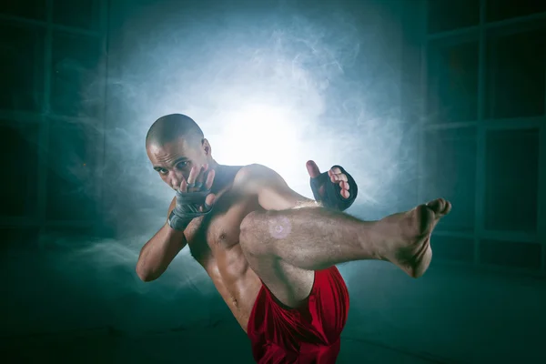 Den unge mannen kickboxning i blå rök — Stockfoto