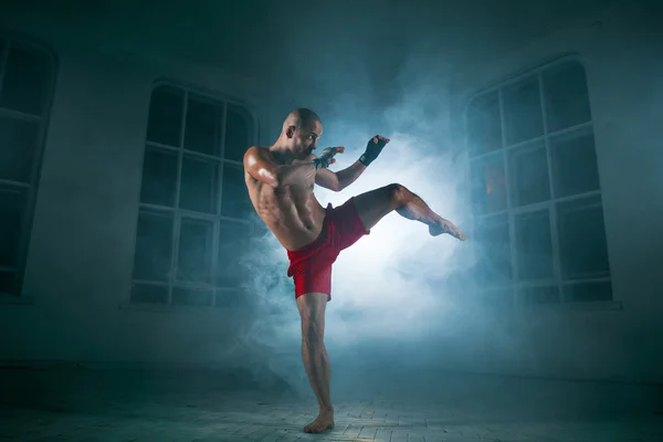 The young man kickboxing in blue smoke — Stock Photo, Image