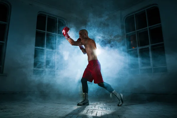 Der junge Mann kickboxt in blauem Rauch — Stockfoto