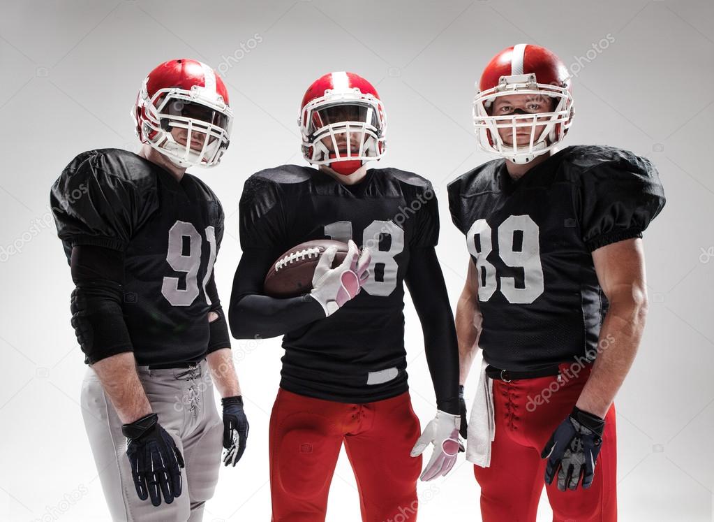 The three american football players posing with ball on white background