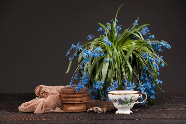 Té con limón y ramo de prímulas azules sobre la mesa — Foto de Stock