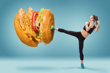Fit, young, energetic woman boxing hamburger as unhealthy food clipart