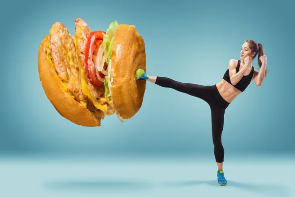 Energiek, fit, jonge vrouw boksen hamburger als ongezond voedsel — Stockfoto