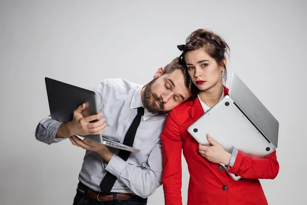 Le jeune homme d'affaires et femme d'affaires avec des ordinateurs portables posant sur fond gris — Photo