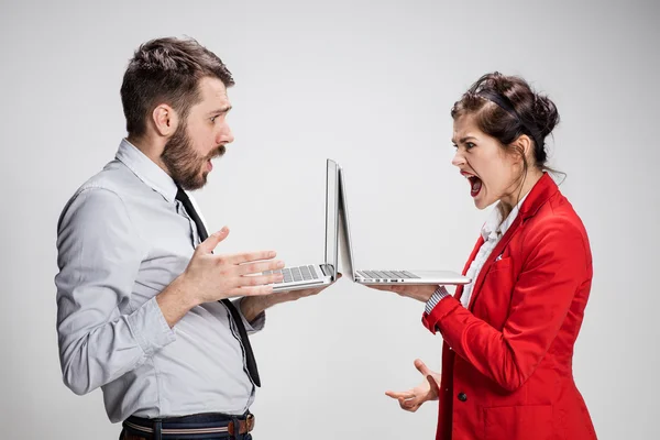 Le jeune homme d'affaires et femme d'affaires avec des ordinateurs portables sur fond gris — Photo