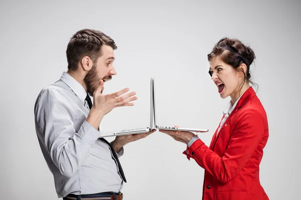 O jovem homem de negócios e mulher de negócios com laptops em fundo cinza — Fotografia de Stock