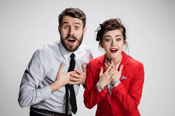 Pria dan wanita bisnis yang terkejut tersenyum dengan latar belakang abu-abu — Stok Foto