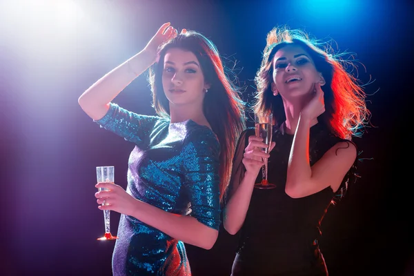 Dos hermosas chicas bailando en la fiesta bebiendo champán — Foto de Stock