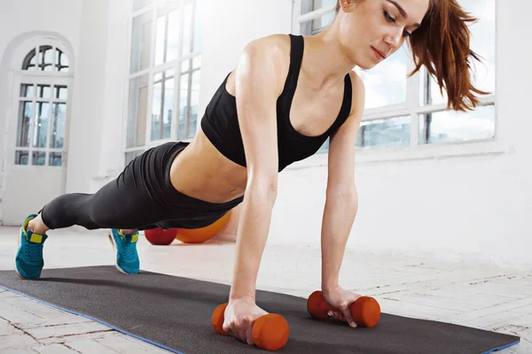 Vacker smal brunett gör några armhävningar en gymmet — Stockfoto