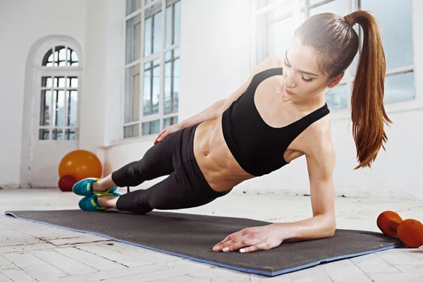 Hermosa morena delgada haciendo algunos flexiones en el gimnasio — Foto de Stock