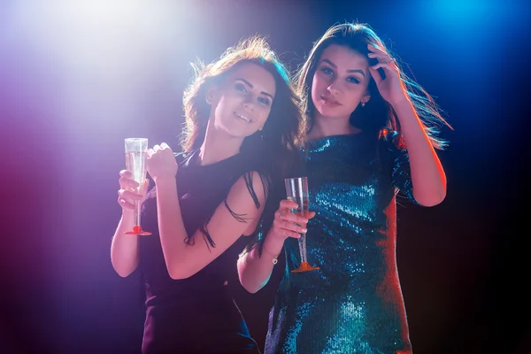 Dos hermosas chicas bailando en la fiesta bebiendo champán — Foto de Stock