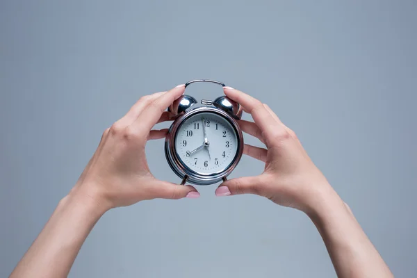 De vrouwelijke handen en oude stijl wekker — Stockfoto