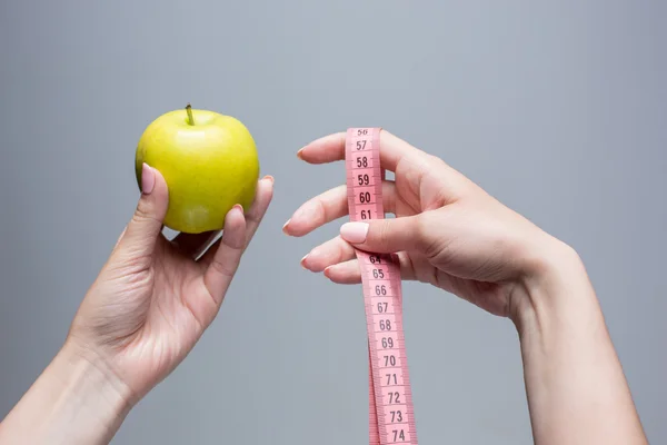 Manzana verde en manos femeninas sobre fondo gris. pérdida de peso, dieta — Foto de Stock