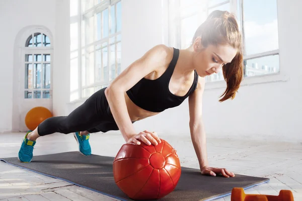 Beautiful slim brunette doing some gymnastics at the gym — Stock Photo, Image