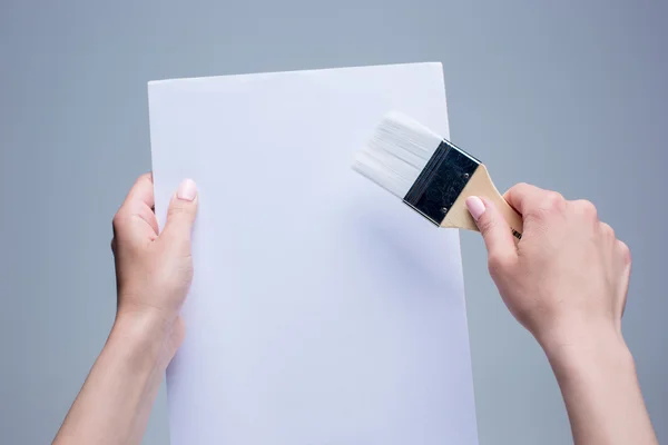 Handen met schilderij borstel op witte doek — Stockfoto