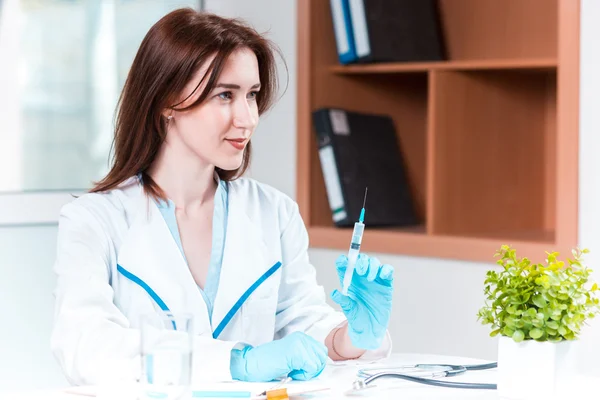 Handen i blå handske anläggning spruta mot vita medicinska klänning — Stockfoto