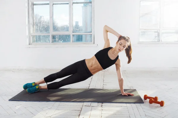 Hermosa morena delgada haciendo algunos flexiones en el gimnasio — Foto de Stock