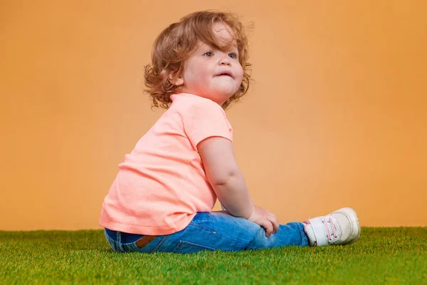 Jedna roztomilá holčička na oranžovém pozadí — Stock fotografie