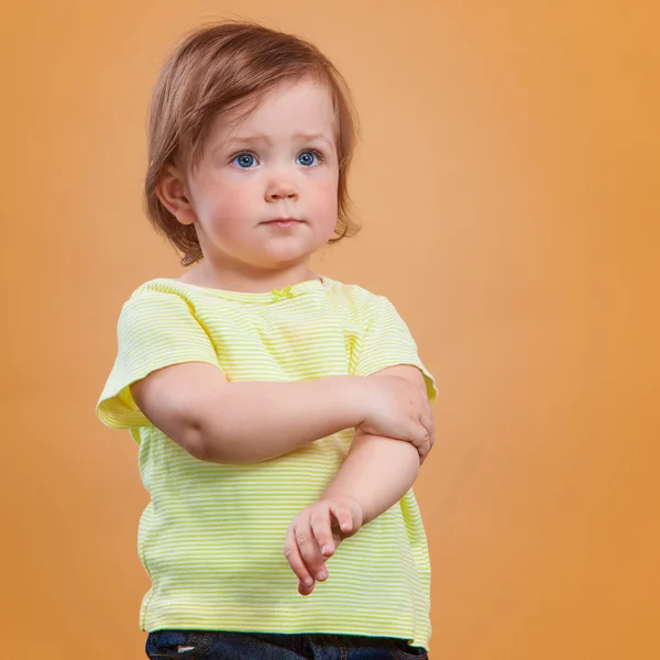 Um bebê bonito menina no fundo laranja — Fotografia de Stock