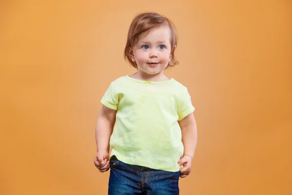 Одна милая девочка на оранжевом фоне — стоковое фото