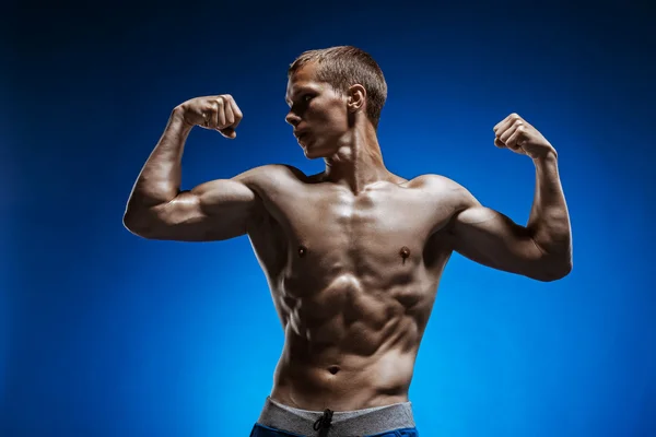 Fitter junger Mann mit schönem Oberkörper auf blauem Hintergrund — Stockfoto