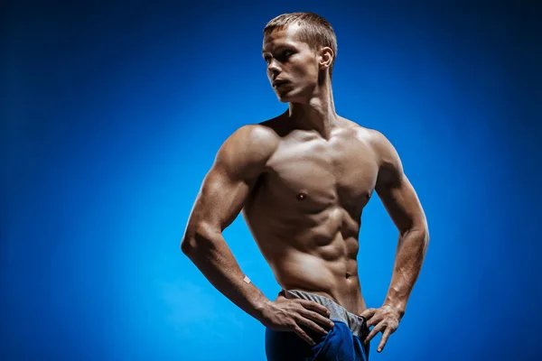 Fitter junger Mann mit schönem Oberkörper auf blauem Hintergrund — Stockfoto