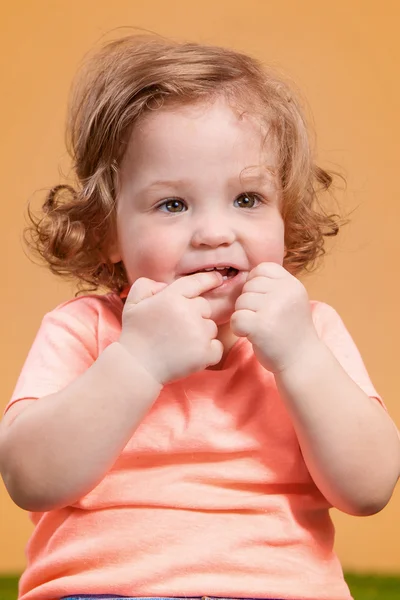 Um bebê bonito menina no fundo laranja — Fotografia de Stock