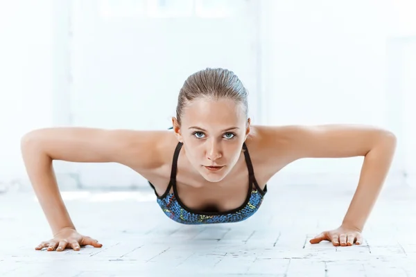 Hermosa morena delgada haciendo algunas flexiones en el gimnasio — Foto de Stock