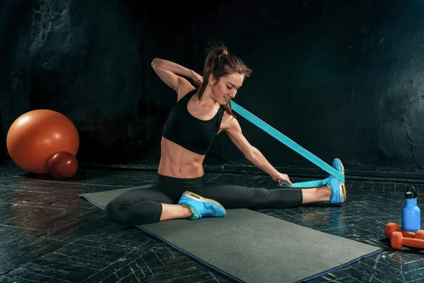 The brunette athletic woman exercising with rubber tape — Stock Photo, Image