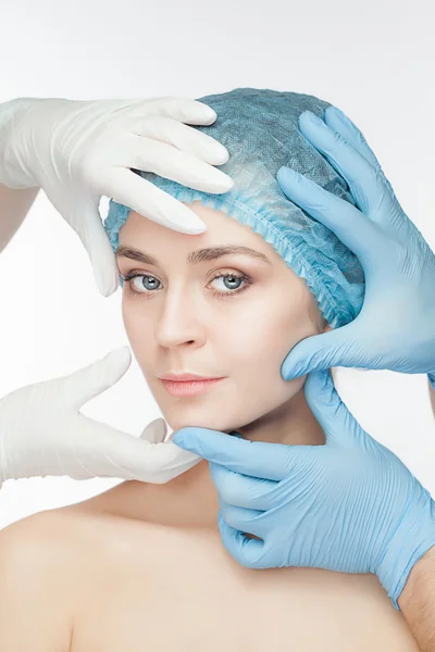 Plastic surgery concept. Doctor hands in gloves touching the beautiful woman face on white — Stock Photo, Image