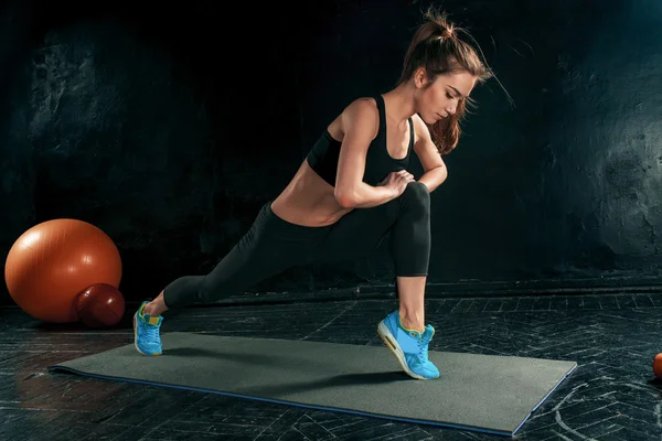 Güzel ince esmer, spor salonunda esneme egzersizleri yapıyor.