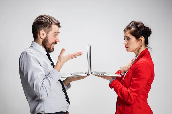 Il giovane uomo d'affari e donna d'affari con computer portatili su sfondo grigio — Foto Stock