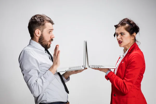 Il giovane uomo d'affari e donna d'affari con computer portatili che comunicano su sfondo grigio — Foto Stock