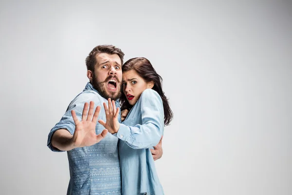 Gros plan Choqué jeune couple avec la bouche et les yeux grand ouvert regardant la caméra sur fond gris . — Photo