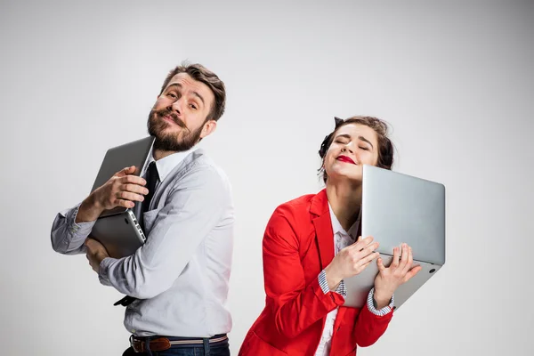 Il giovane uomo d'affari e donna d'affari con computer portatili su sfondo grigio — Foto Stock