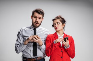 İş kavramı. Cep telefonu gri arka plan üzerinde tutan iki genç arkadaşları