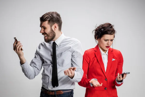 Affärsidé. De två unga kollegor håller mobiltelefoner på grå bakgrund — Stockfoto