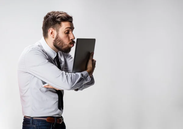 O jovem empresário com laptops beijando tela no fundo cinza — Fotografia de Stock