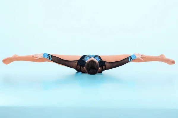 Девушка танцует гимнастику на синем фоне — стоковое фото