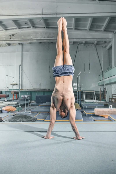 Caucásico hombre gimnasia acrobacias equilibrio postura en gimnasio fondo — Foto de Stock