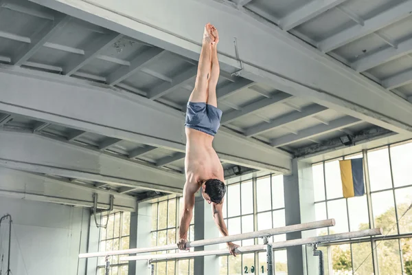 Gimnasta masculino haciendo handstand en barras paralelas —  Fotos de Stock