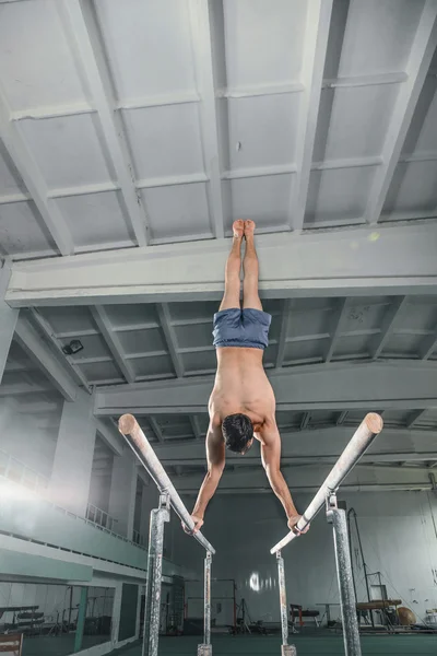 Чоловіча гімнастка виконує ручку на паралельних брусках — стокове фото