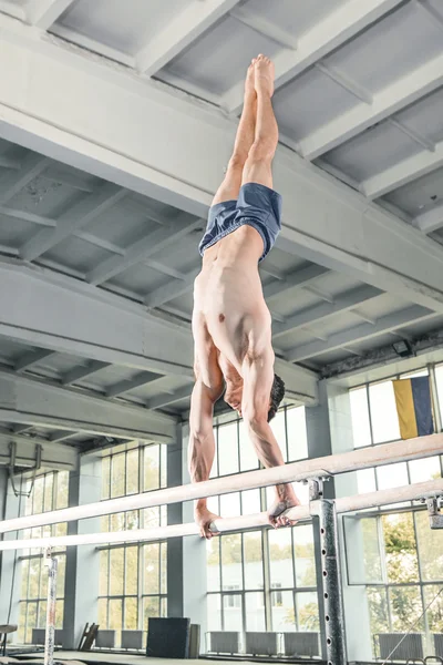 Мужчина гимнаст, выступающий на параллельных брусьях — стоковое фото