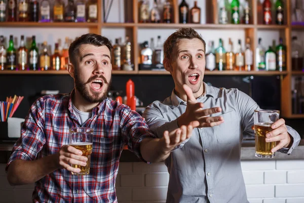 Jovens com cerveja assistindo futebol em um bar — Fotografia de Stock