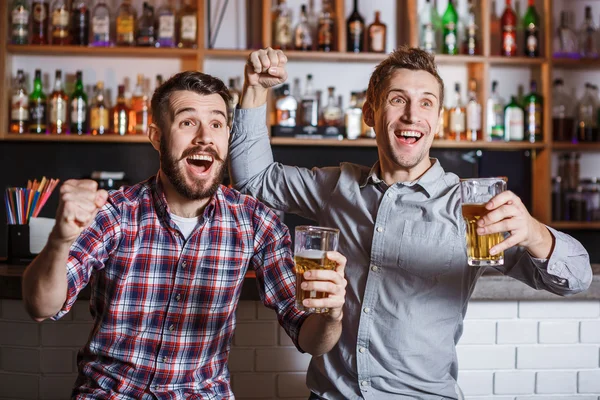 Jovens com cerveja assistindo futebol em um bar — Fotografia de Stock