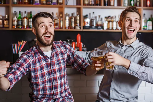 Jovens com cerveja assistindo futebol em um bar — Fotografia de Stock