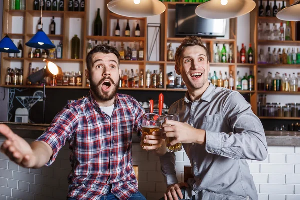 Jonge mensen met bier voetbal in een bar kijken — Stockfoto
