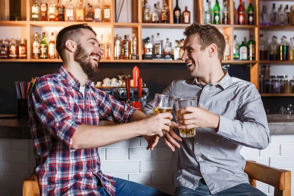 Amigos felizes bebendo cerveja no balcão no pub — Fotografia de Stock