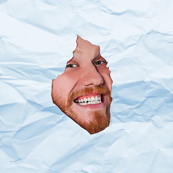 Young man looking through paper rip — Stock Photo, Image