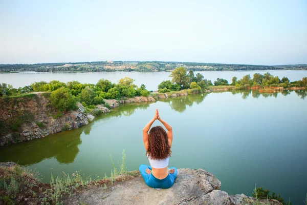 Молодая женщина практикует йогу возле реки — стоковое фото